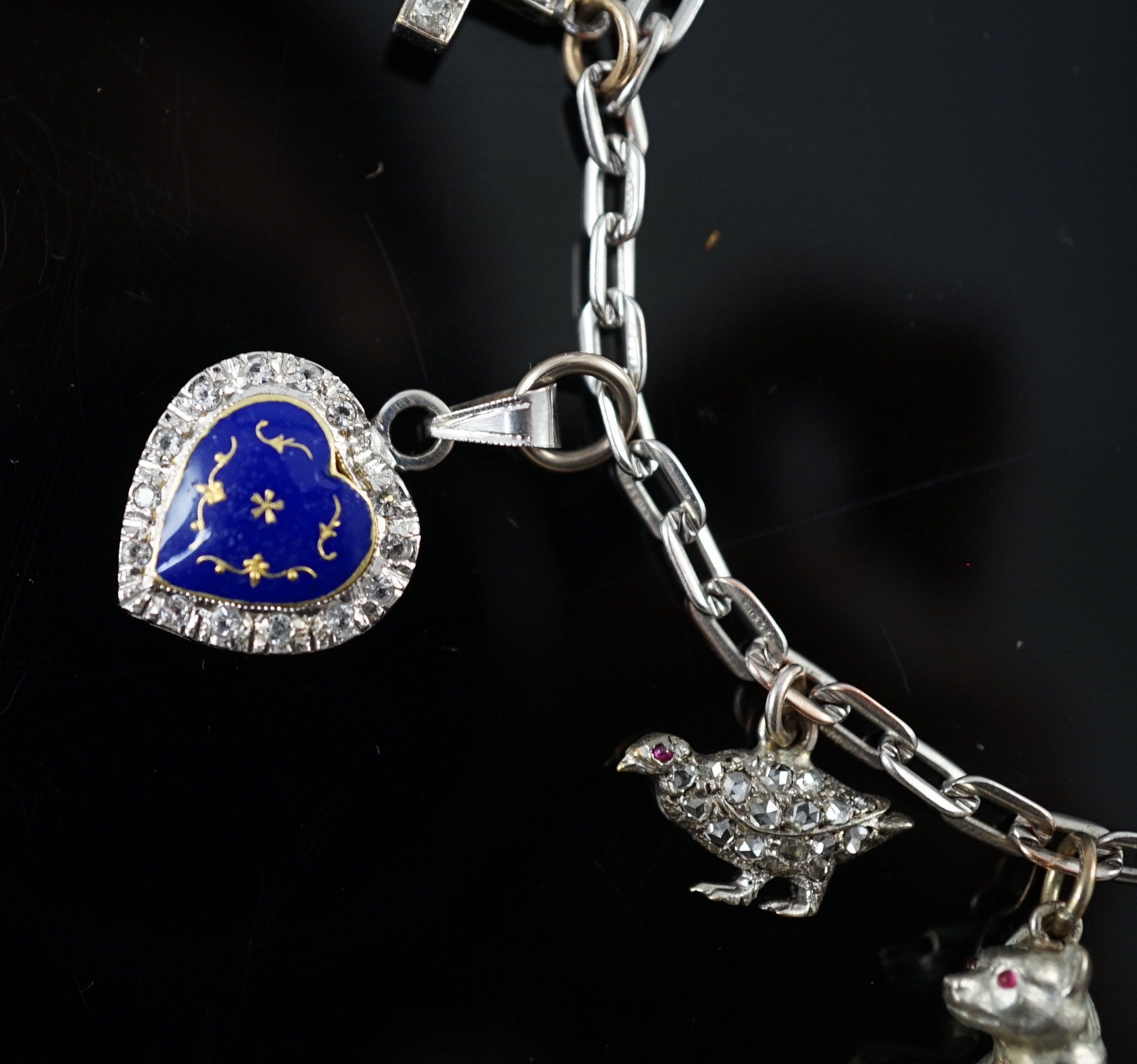 A 9ct white gold charm bracelet, with French platinum and diamond set clasp and hung with nine assorted charms, eight set with diamonds